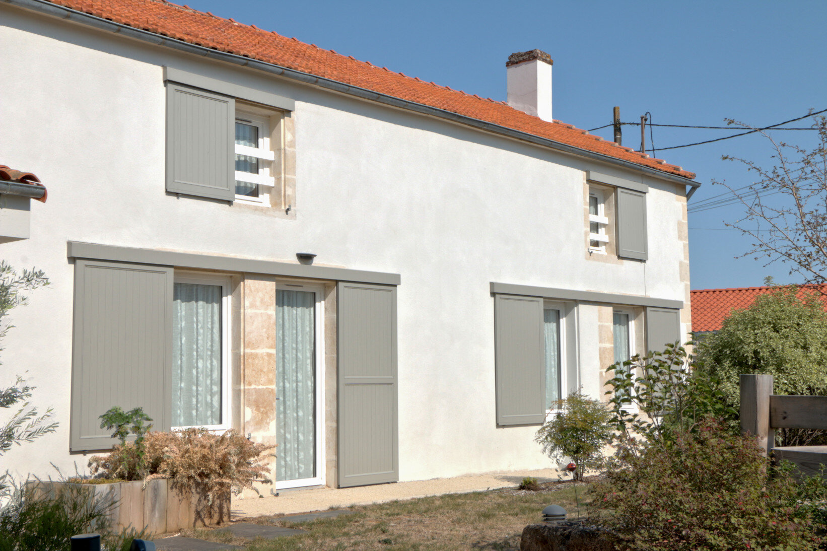 Stilvolle Außenterrasse mit Lamellendach und Beleuchtung Modernes Haus mit minimalistischen hellgrauen Schiebeläden